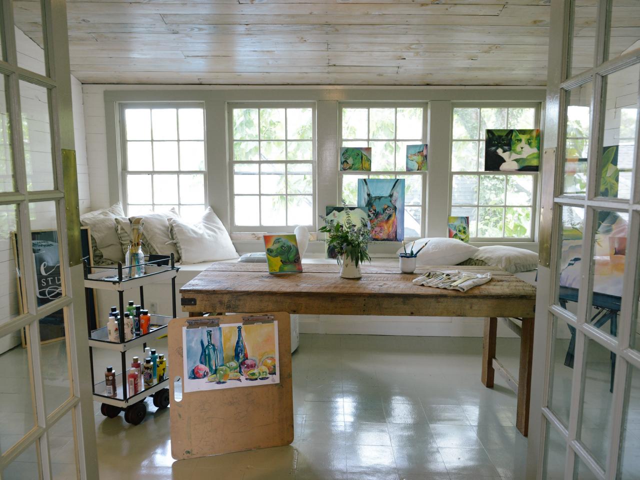 An artists studio with water colours against a wall of windows.