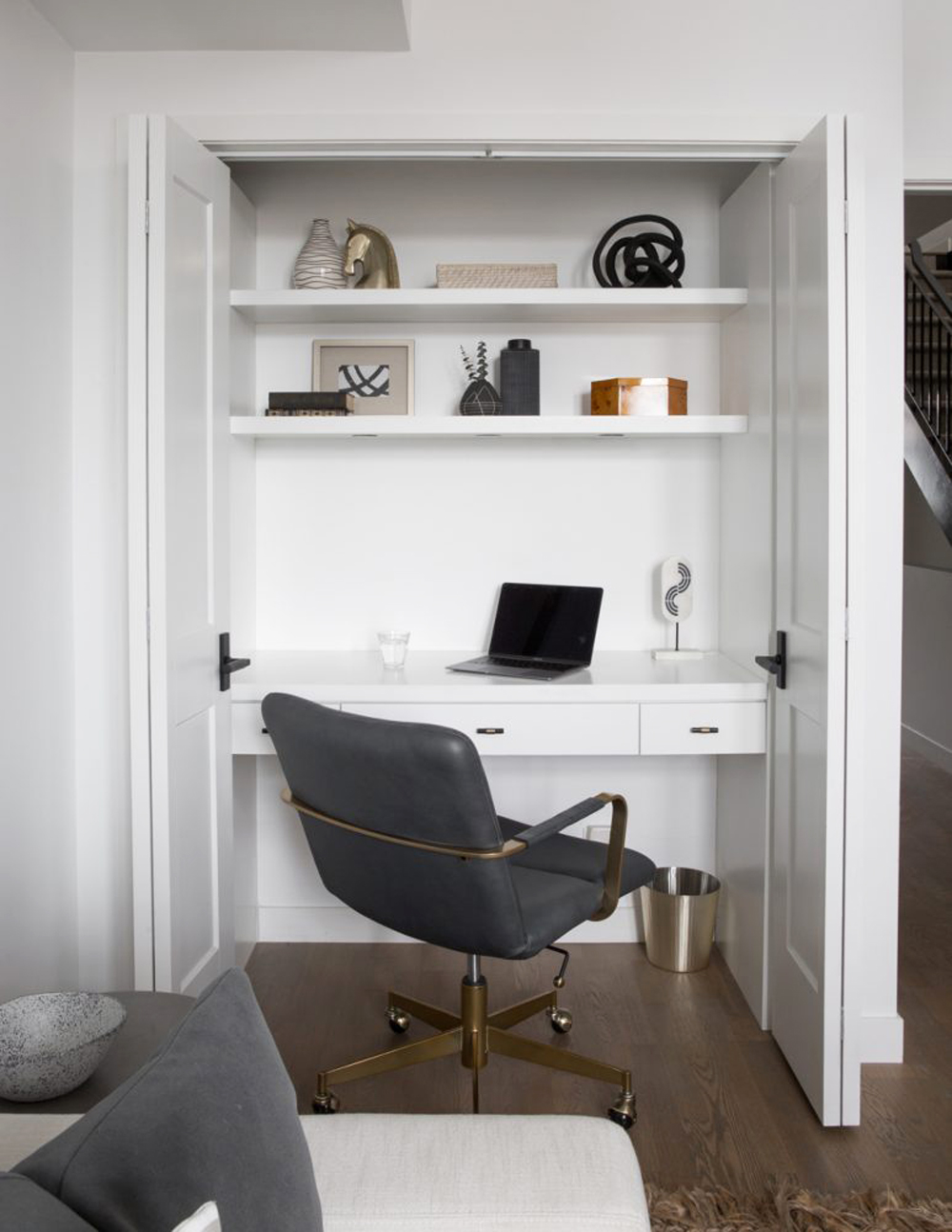 A simple white office space inside of a tiny bedroom closet with shelving and wheeled office chair