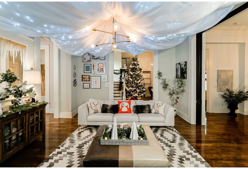 Christmas decor in an open concept living room, complete with twinkle lights along the ceiling