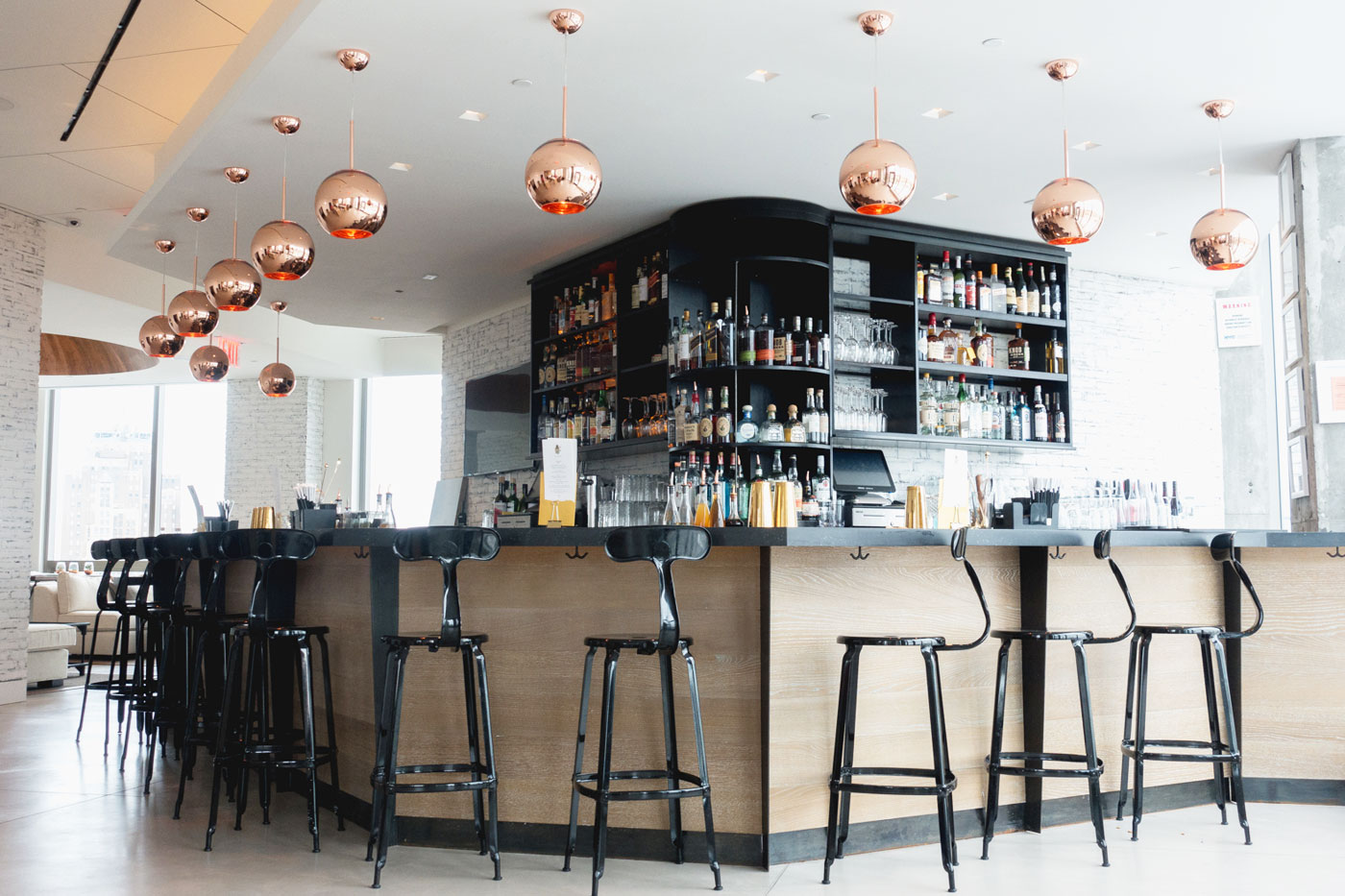 bar with black stools and copper lights