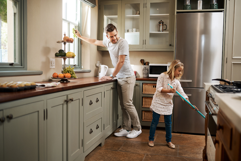 man and child cleaning modern kitchen with green cabinets