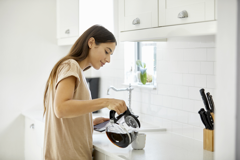 Woman pouring coffee in modern white kitchen