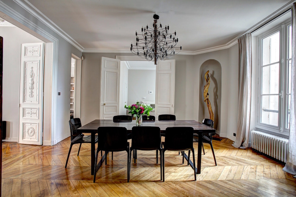 White dining room with hardwood floors and black light fixture