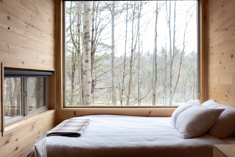 White bed in front of window in rustic wood bedroom
