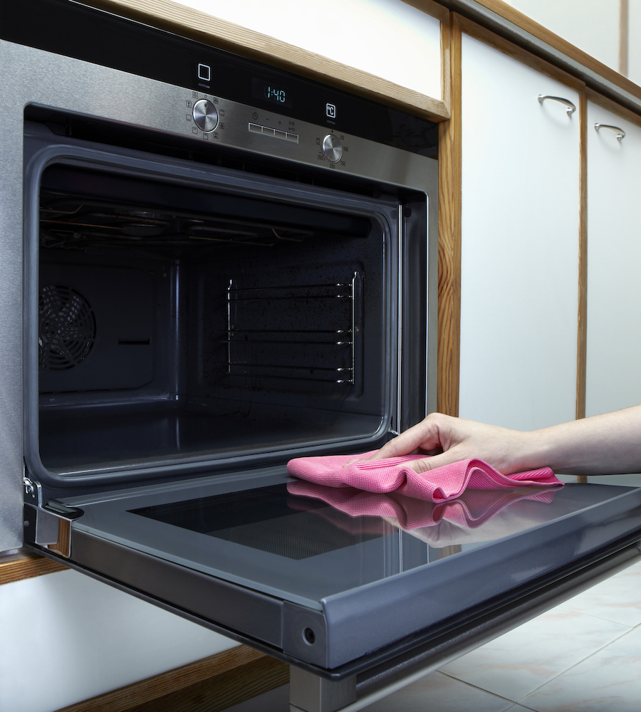 Pink-gloved hands cleaning inside oven