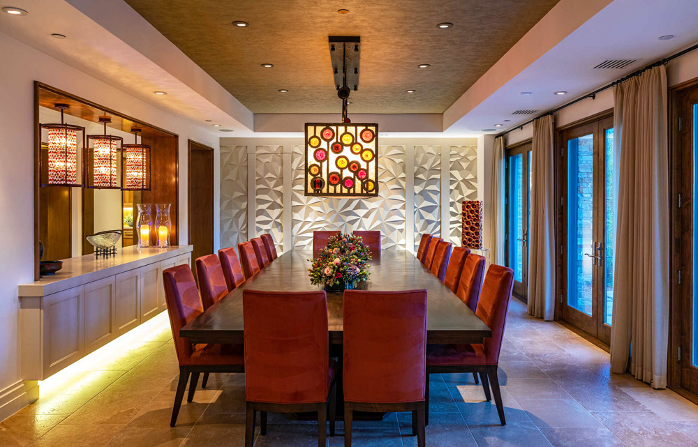 A dining room with bold light fixtures and plush chairs with seating for 16 guests