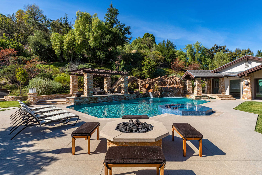 A sweeping view of the backyard, including a modest swimming pool next to a pergola and lawn furniture