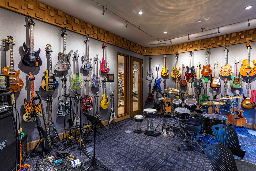 A basement music room with wall mounted guitars and drum kit
