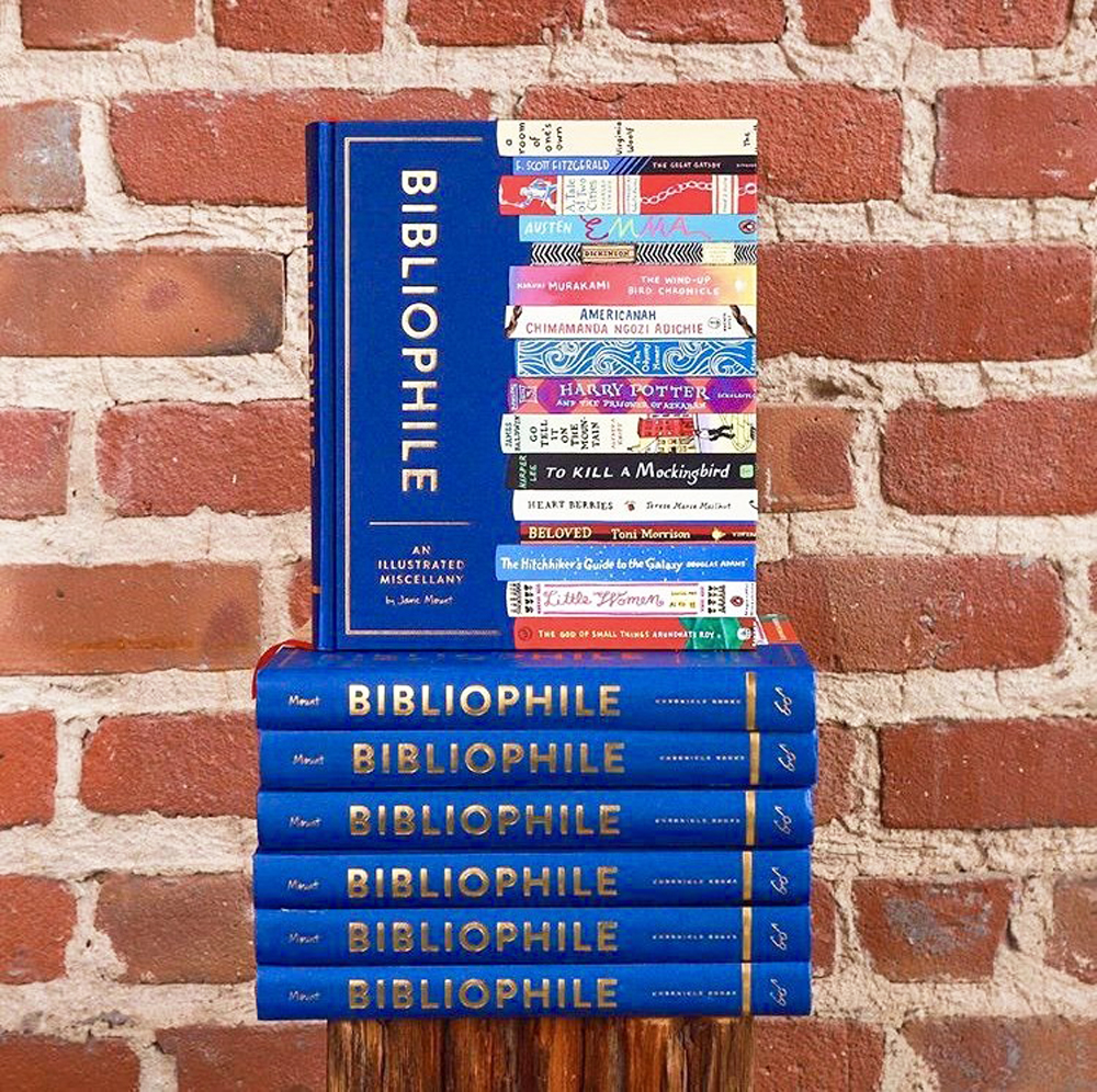 A stack of bright blue coffee table books leaning against a wall of exposed bricks