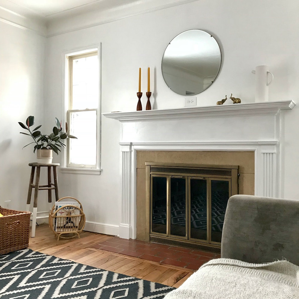 white living room with fireplace, wicker basket and magazine rack