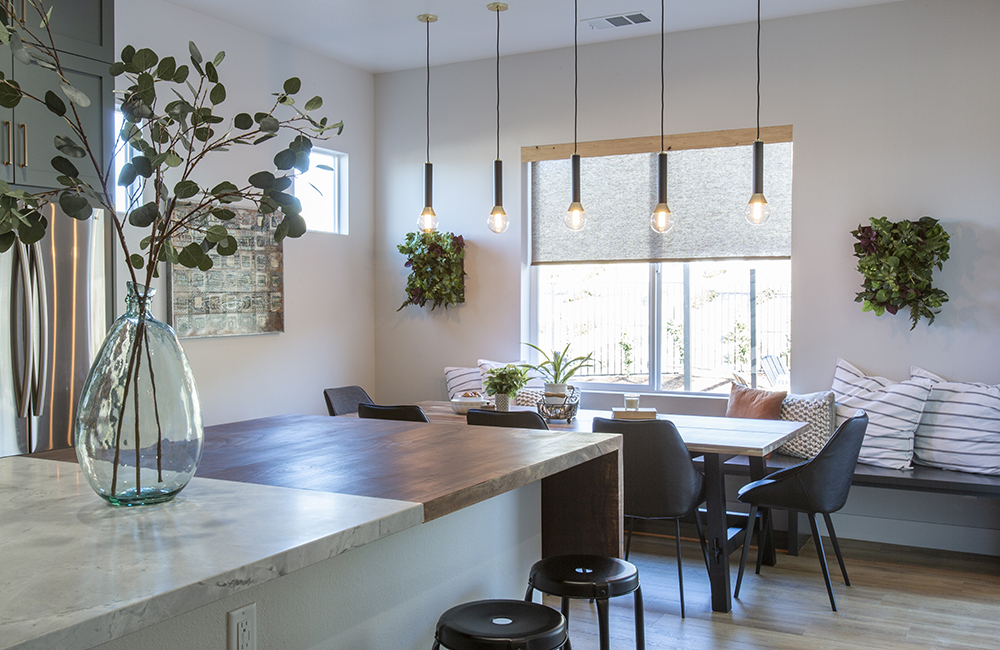 A brightly lit dining room with pendant lighting and a marble and wood kitchen island