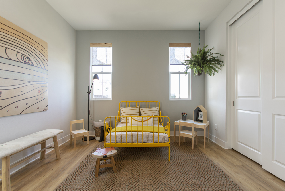 A bright and playful kids' bedroom with neutral area rug, furniture and potted greenery