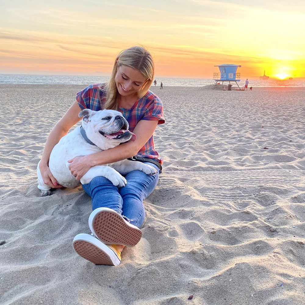 Jasmine Roth smiling on the beach with her bulldog