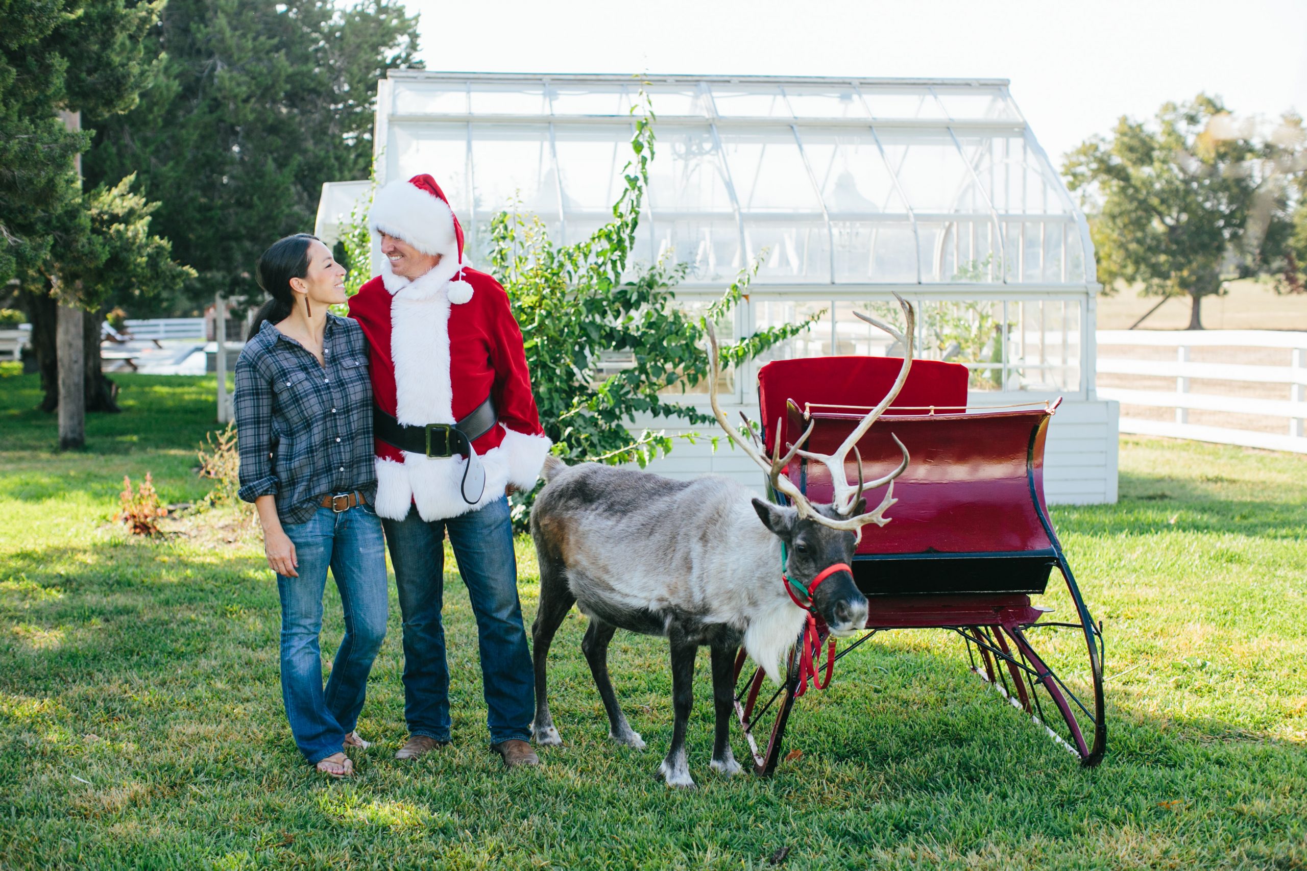 Chip and Joanna Gaines pose with a Reindeer and a holiday sleigh for Christmas.