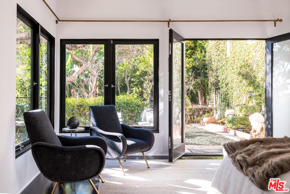 A sitting area in the master bedroom with French doors leading out into a backyard space