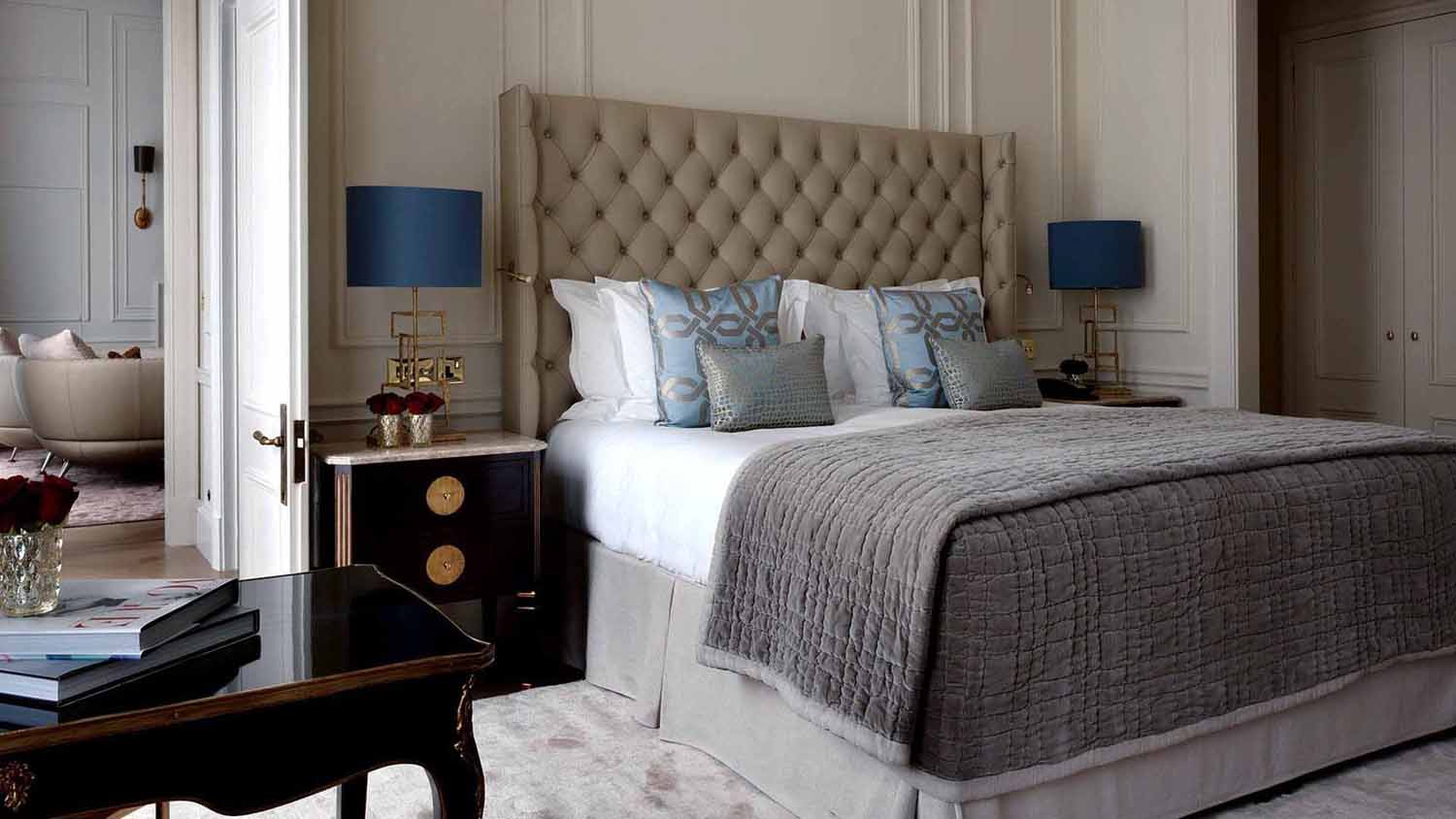 grey bedroom with tufted headboard and two blue shade lamps