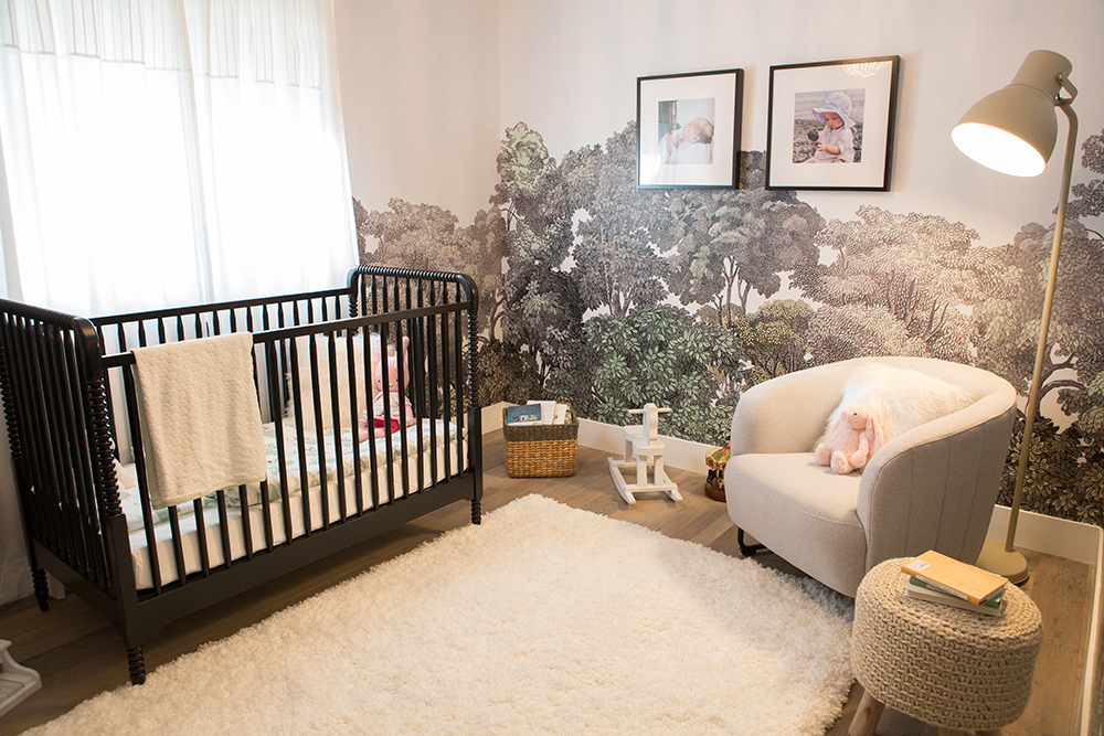 chic nursery with trees on walls, black crib and white area rug