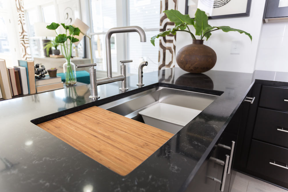 modern kitchen with bamboo insert in metal sink on black counter