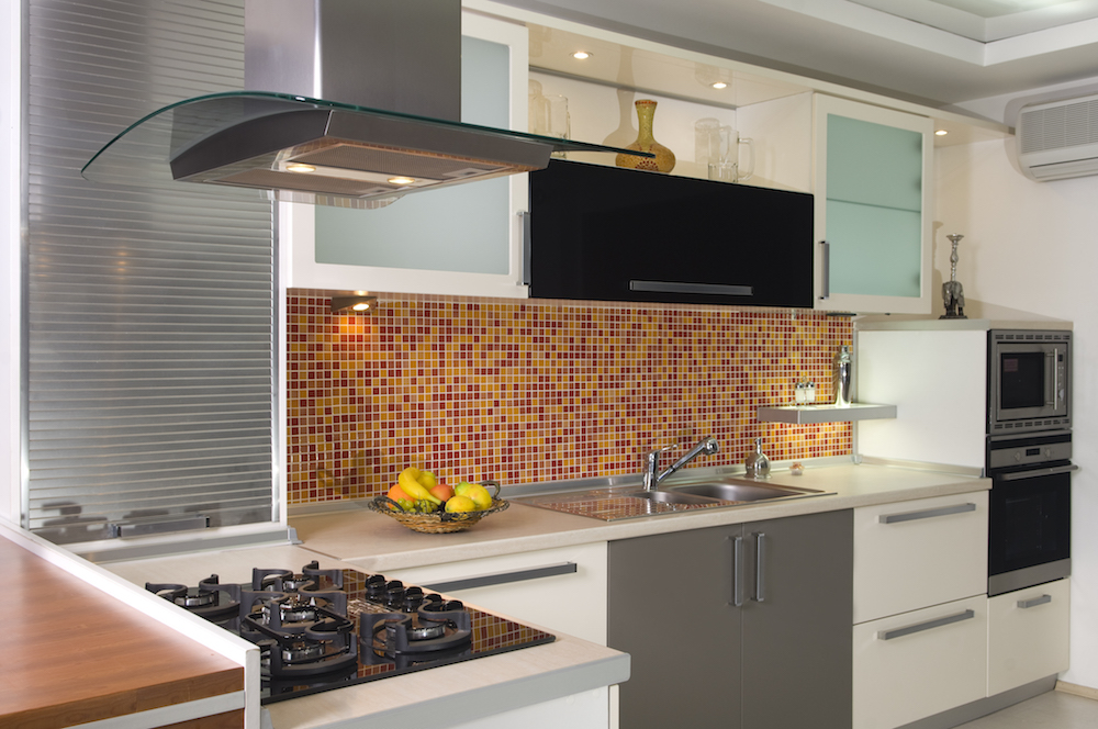 eclectic kitchen with red and orange tiles, white cabinets and steel appliances