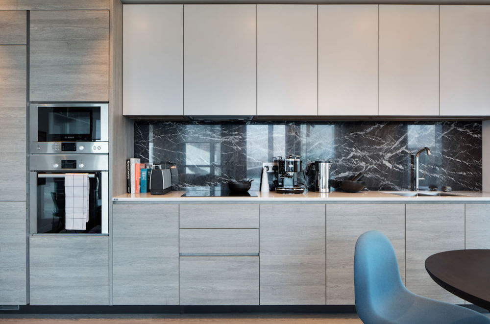 minimalist kitchen with cream cabinetry and black marble backsplash