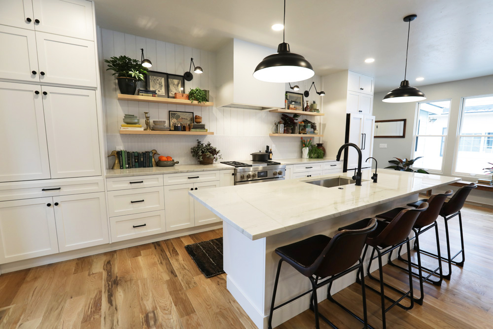 An open-concept all-white kitchen renovation with lots of storage space and floating shelves