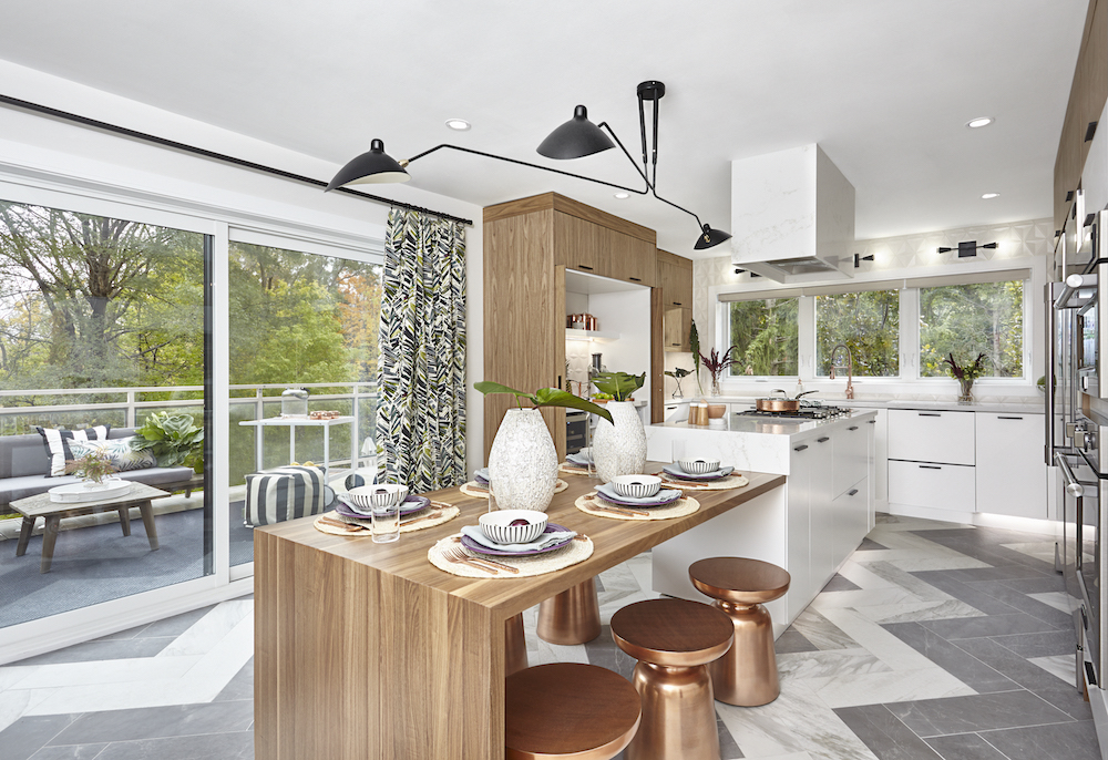 A brightly-lit kitchen with a dining table attached ti the white island with chrome stools