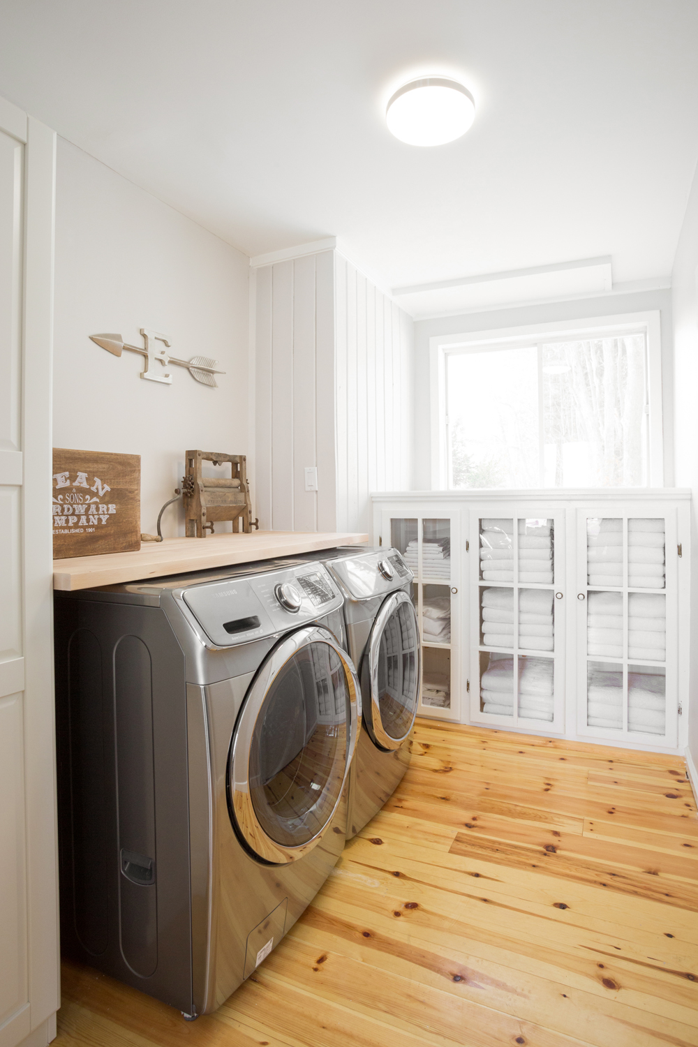 light-filled laundry room with warm wood floors and storage.
