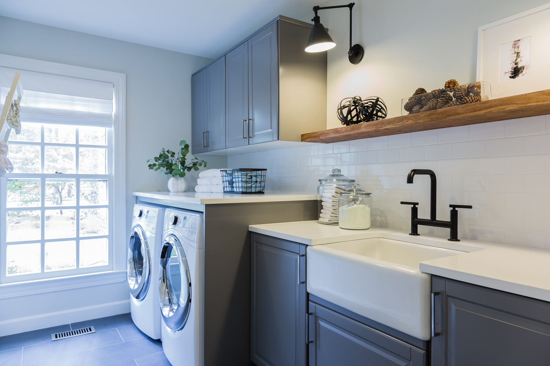 Light-filled laundry room with farmhouse sink and wood open shelving.