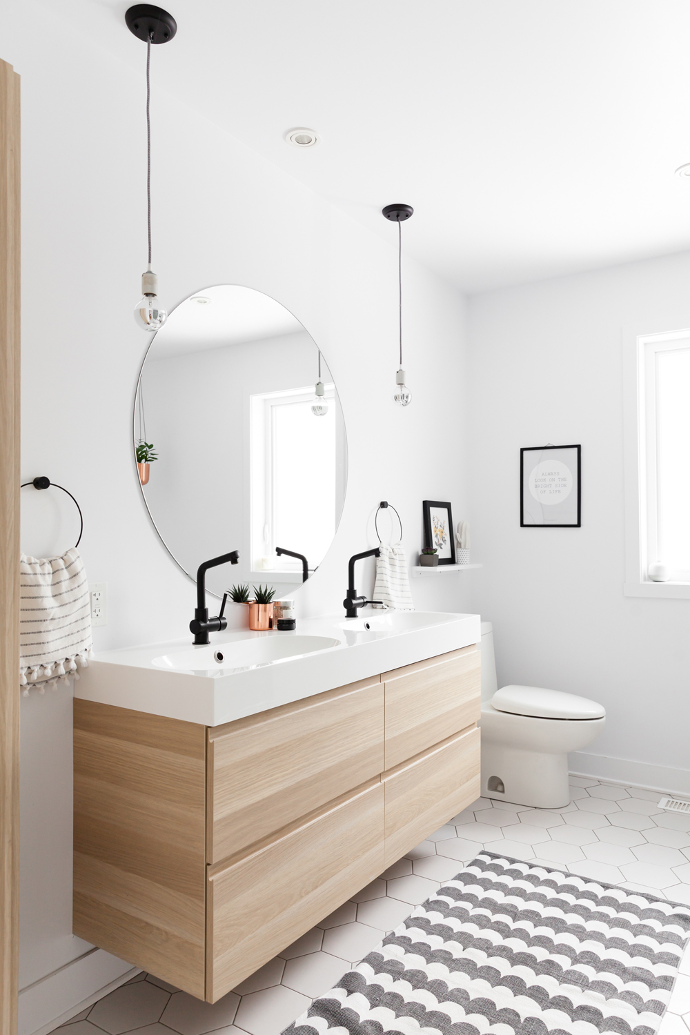 bathroom, big round mirror, lights suspended, floating pale wood vanity with four drawers