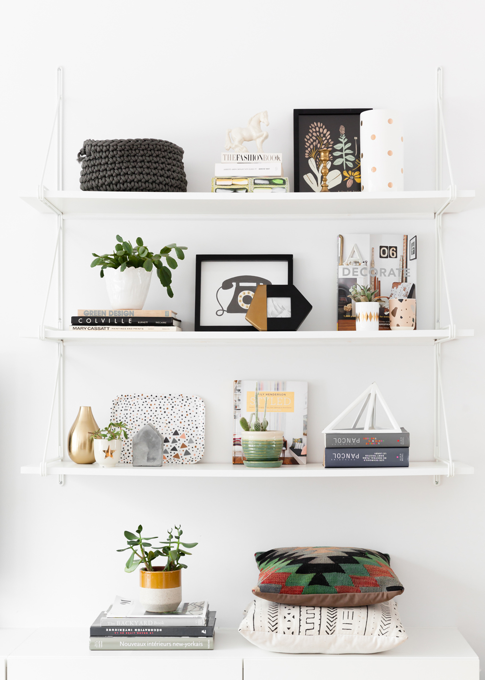 three white shelves with grey nubby knit basket and fashion book on top shelf