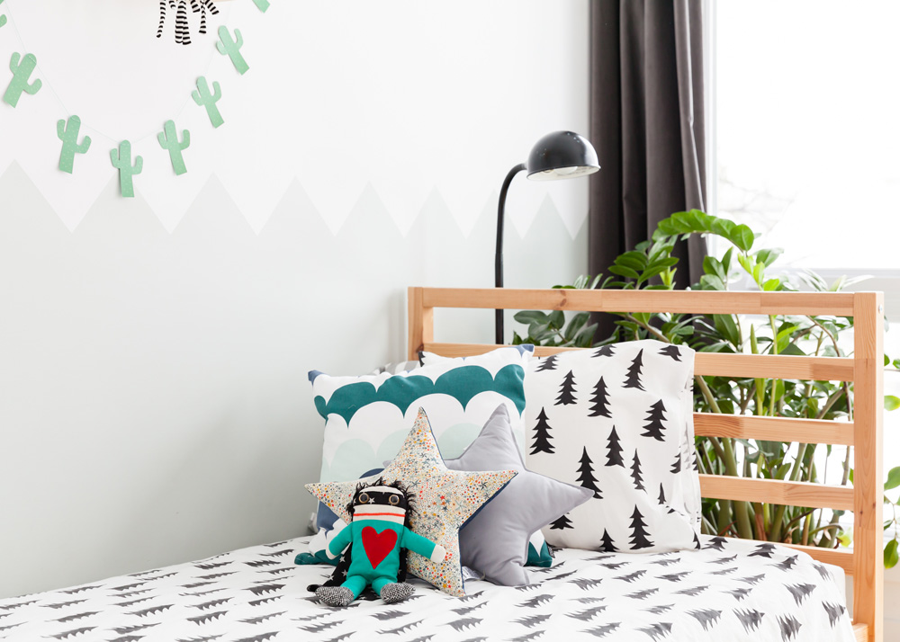 kids bed with pine tree patterned black and white bedding and green cactus cutouts above it