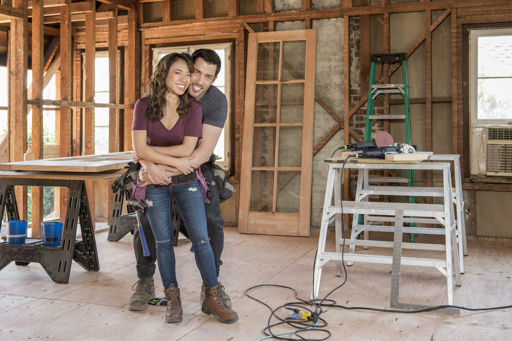 Linda Phan and husband Drew Scott stand in a construction site hugging