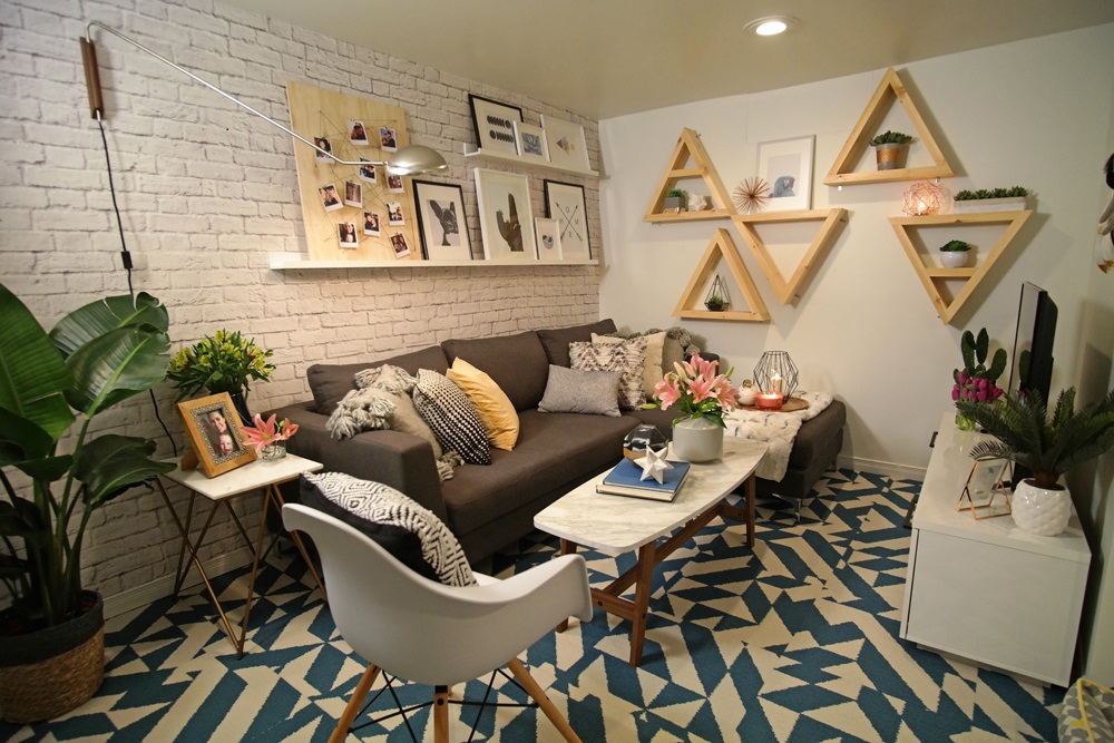 basement with one painted white brick wall blue and white patterned rug and wooden triangles on wall