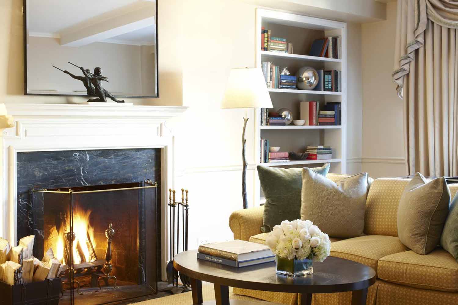 fireplace with fire, built in book shelves and three seat sofa with cushions