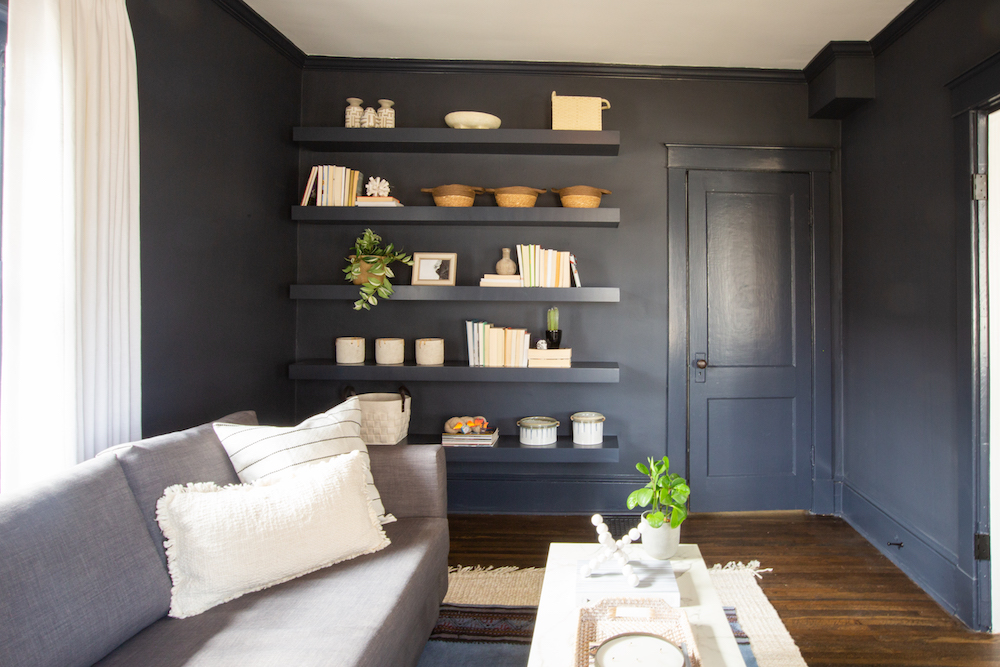 Black walls with shelves and grey couch in an office