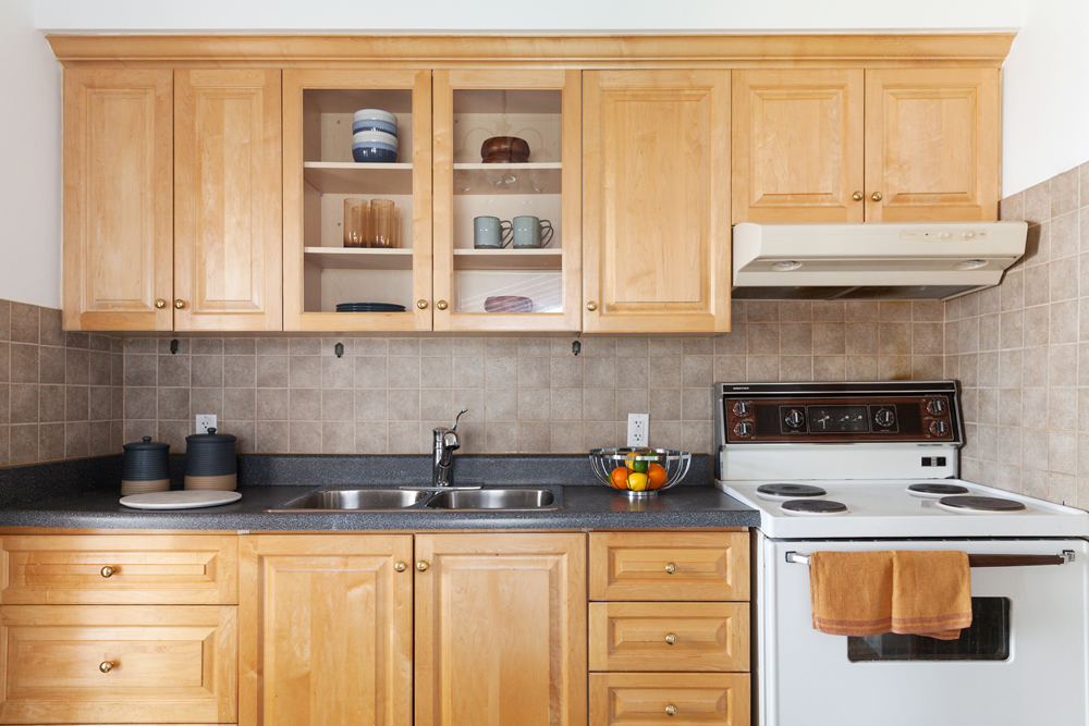A retro-looking kitchen with light brown cabinetry and grey countertop