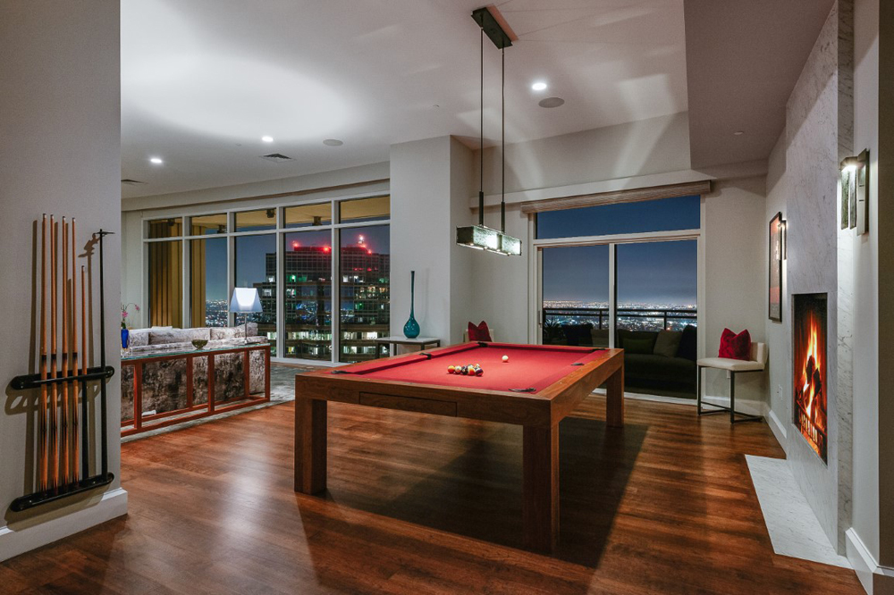 A large red billiards table in front of a faux fireplace in a games room off to the side of the condo living room
