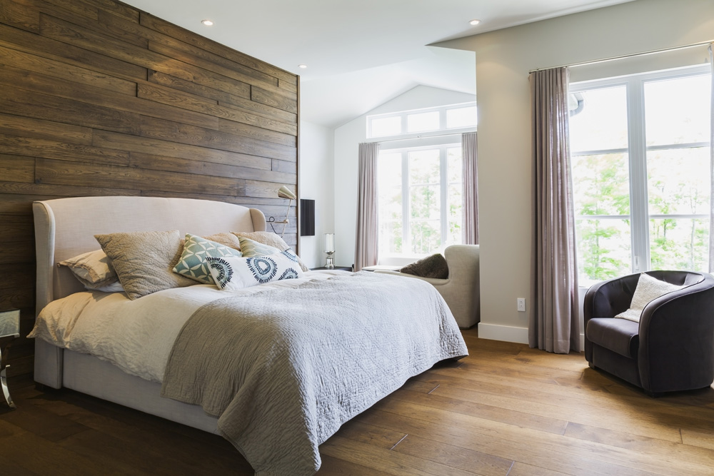 A rustic bedroom with hardwood flooring and large windows