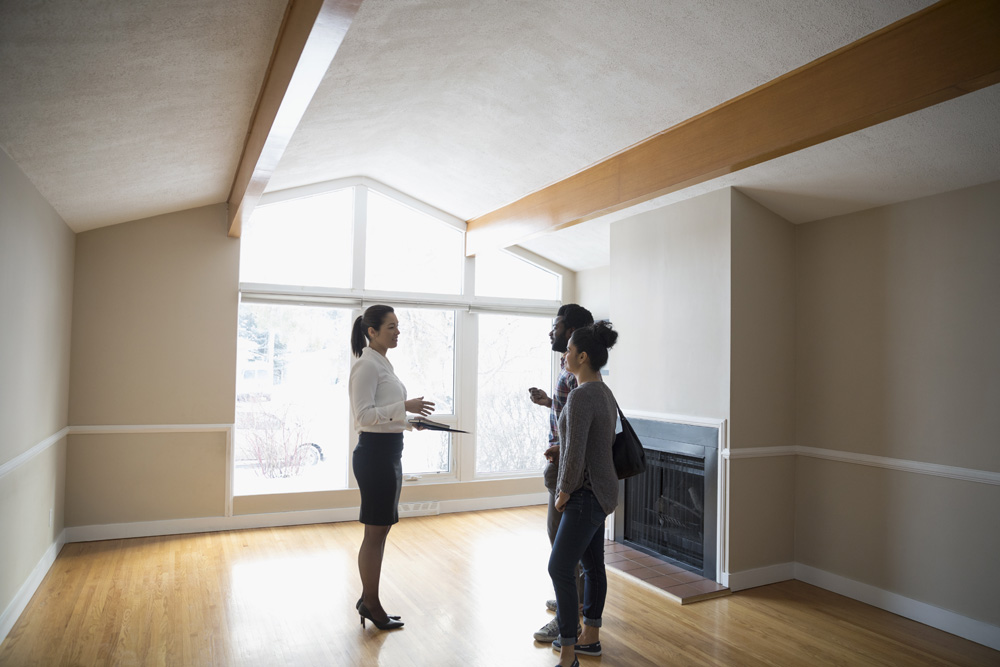 A real estate agent walks a couple through an empty house