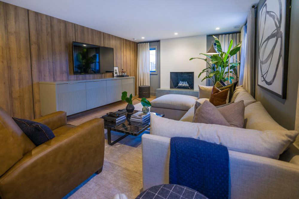 The renovated den features wood paneling on the TV wall and a custom-built media cabinet