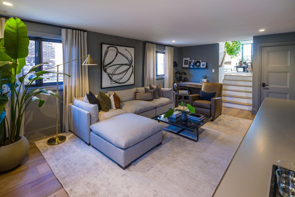 In the renovated den, medium gray walls complement the light gray couch which offers plenty of seating room