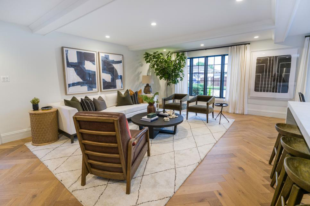 The renovated living room features gorgeous wood floors laid in a herringbone pattern