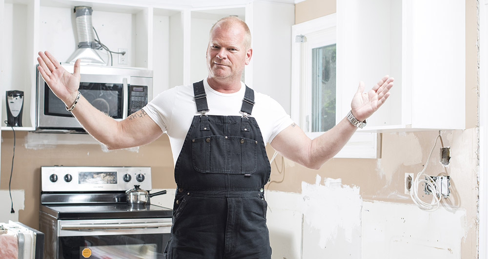 Mike Holmes standing in the middle of an unfinished kitchen