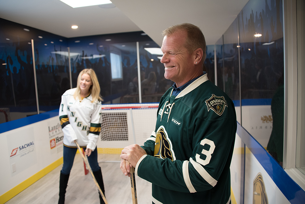 Mike Holmes standing in an indoor ice rink wearing a London Knights jersey