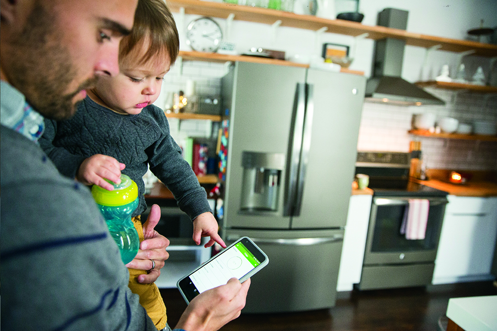 A man holding a young boy in a kitchen with smart appliances