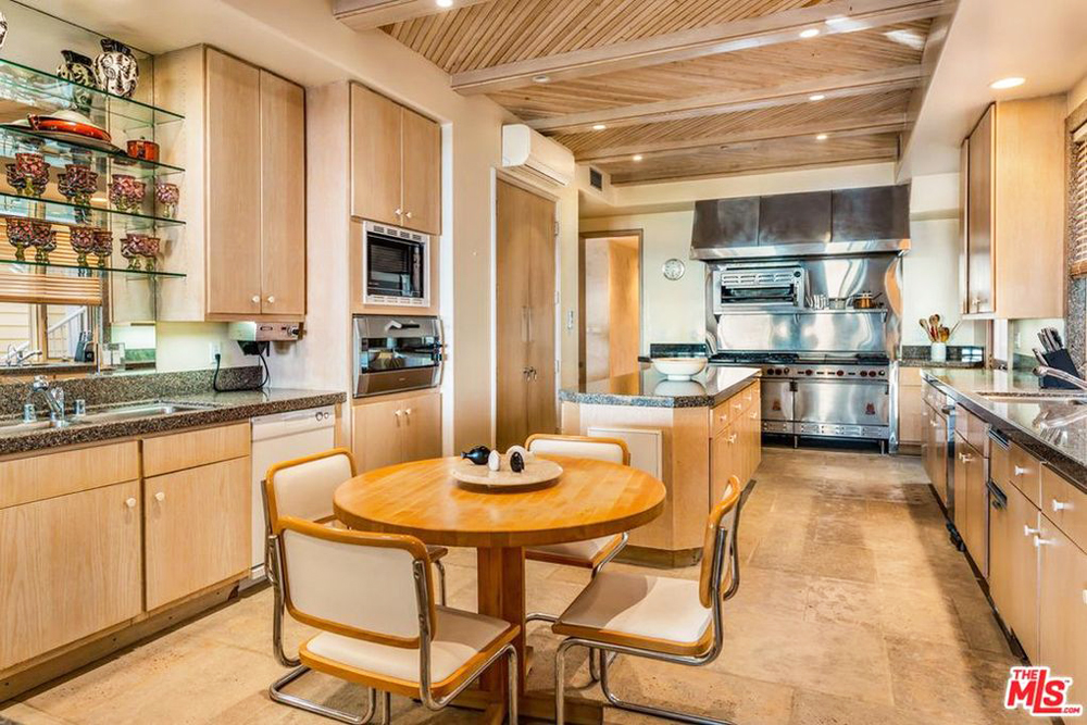 A narrow kitchen space with a breakfast nook, plenty of storage and marble-topped island