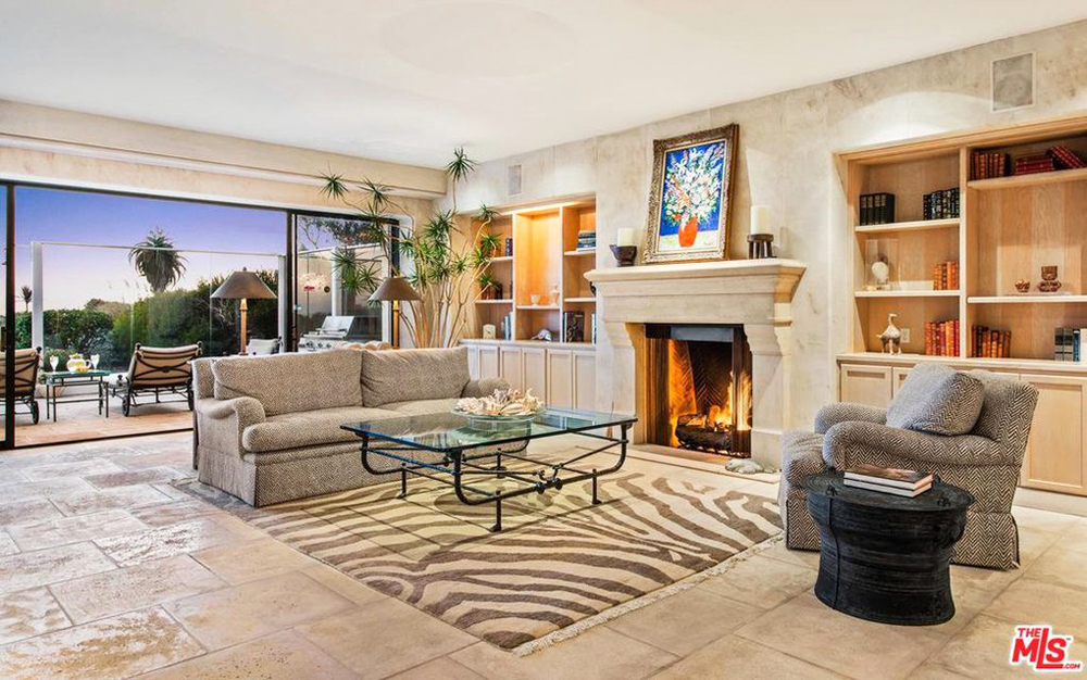 A separate seating area with a wood-burning fireplace with views overlooking the backyard and beach