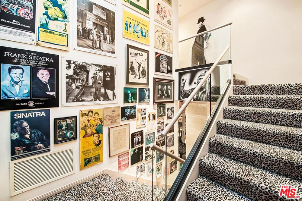A leopard print carpeted staircase leading up to the second level with all the wall space covered in vintage Frank Sinatra posters and memorabilia