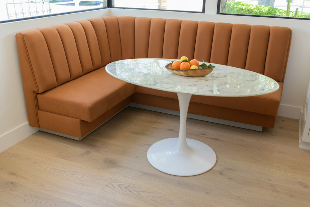 orange upholstered banquette with oval dining table