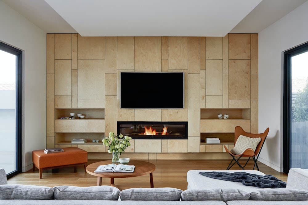 television on wood built-in wall with fireplace and minimal furniture